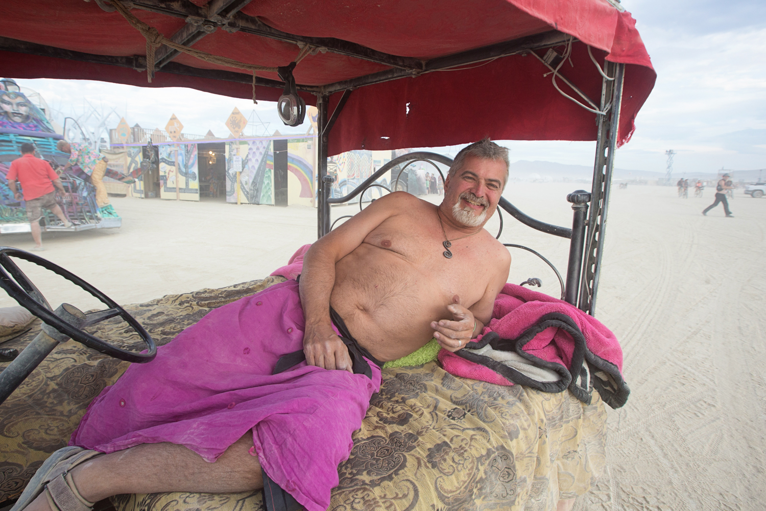 Doug from Seattle lounges in his bed car. An eight-time burner, he likes to keep things simple. There is no engine noise, and no music. Perfect for a low-key cruise of the playa