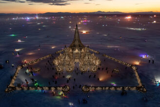 Rendering of Black Rock City the last orange of sundown over the mountains, with The Temple a triangle in the middle.