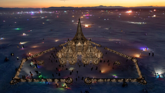 Rendering of Black Rock City the last orange of sundown over the mountains, with The Temple a triangle in the middle.